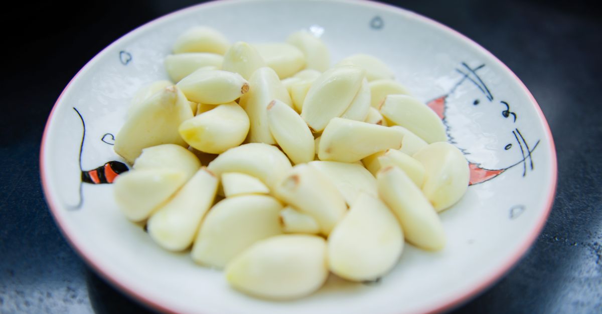 Spicchi d'aglio sbucciati raccolti su un piattino decorato