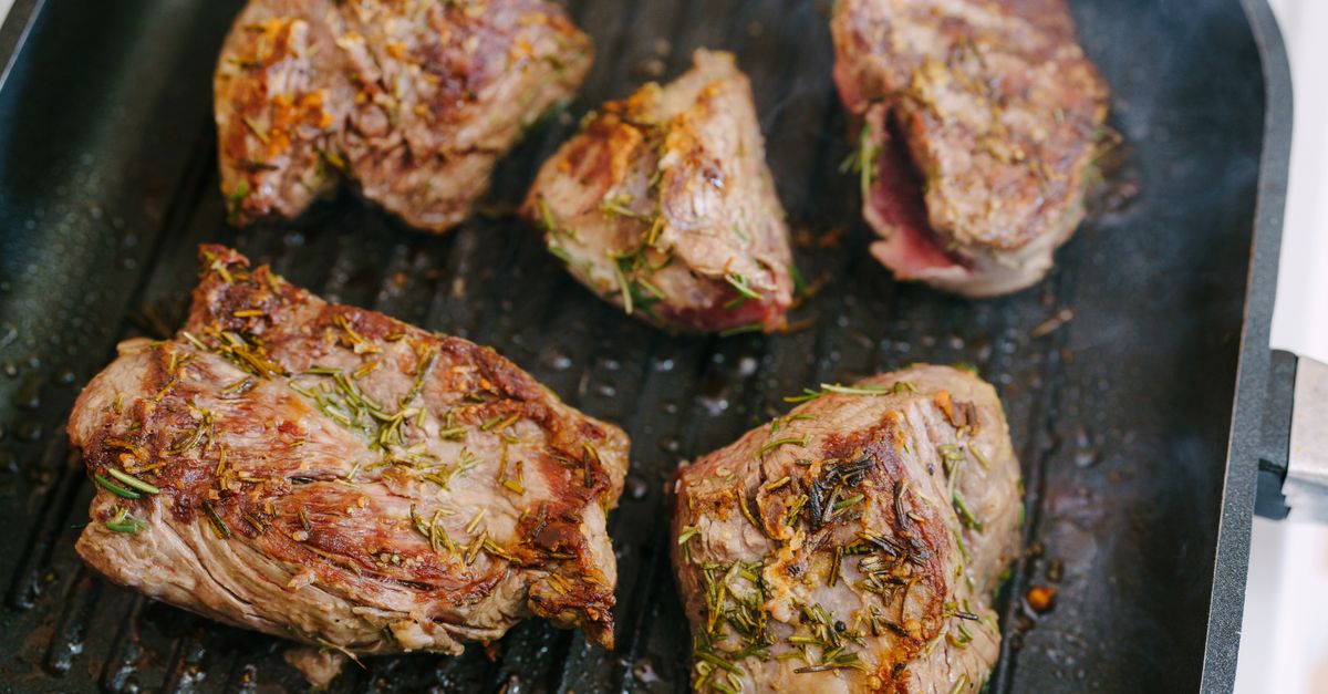 Pezzi di carne marinata con rosmarino ed erbe che cuociono su una griglia