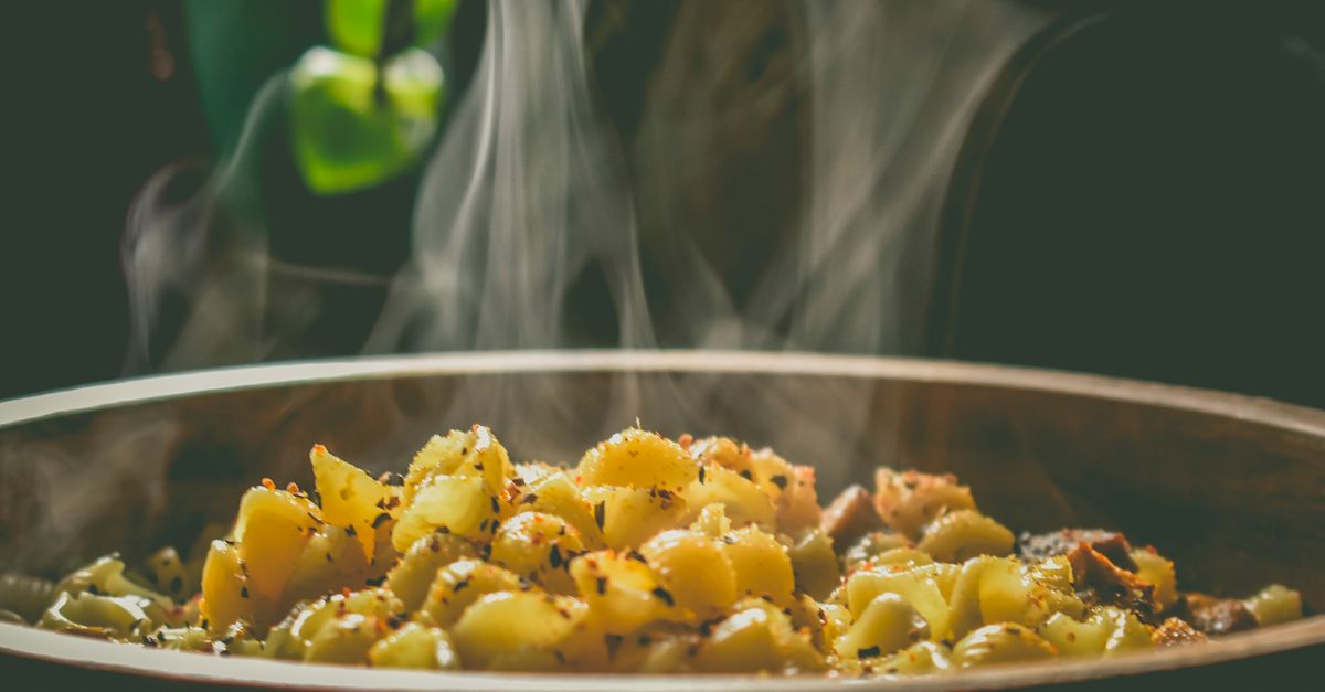 Conchiglie corte con crema e spezie servite in una padella, con vapore che sale visibile sopra il piatto.