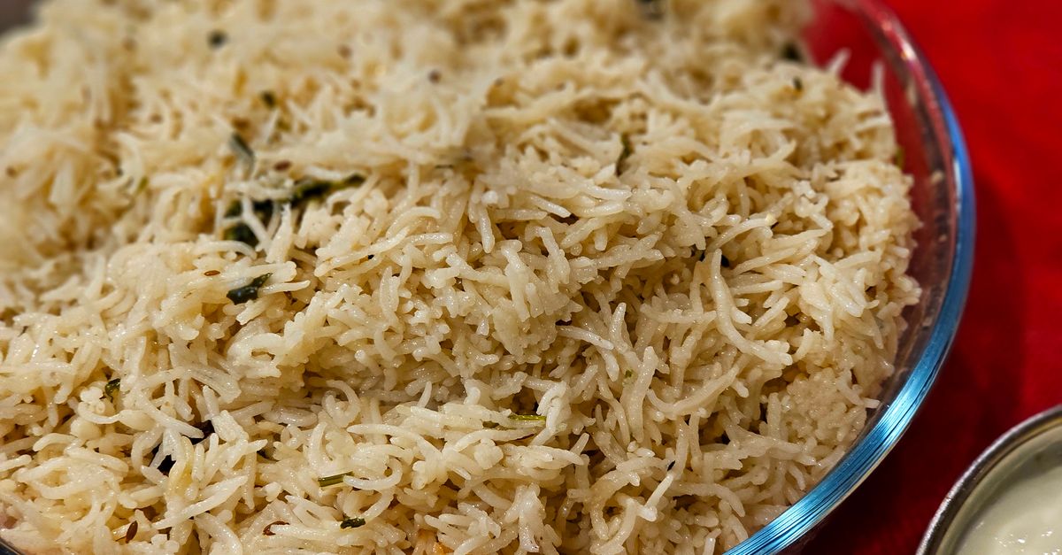 Primo piano di riso basmati cotto e soffice servito in una ciotola di vetro su tovaglia rossa