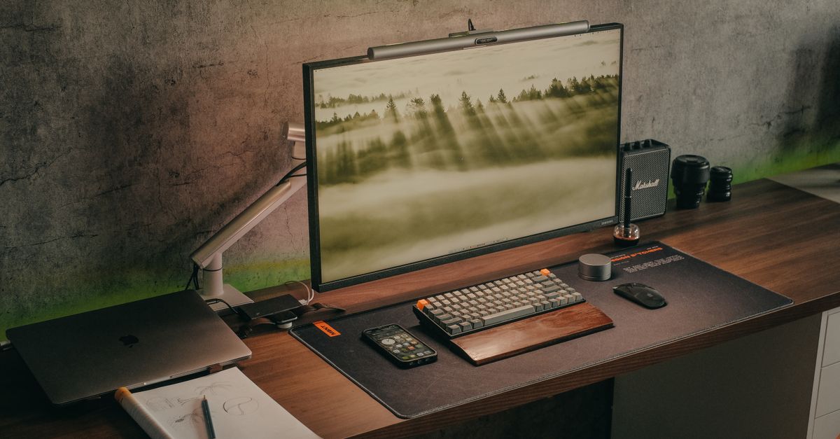 Scrivania in legno con monitor, tastiera, laptop e accessori ordinati, con cavi gestiti in modo discreto sotto il piano di lavoro.