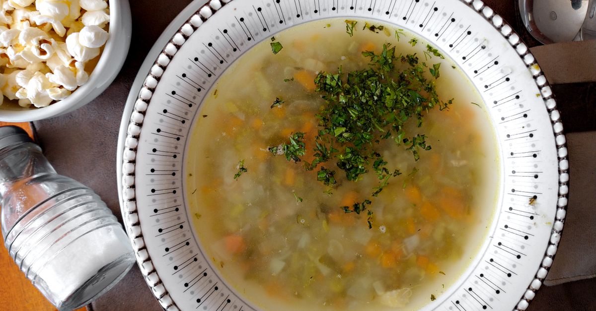 Una zuppa di verdure calda in un piatto decorato, guarnita con prezzemolo tritato fresco.